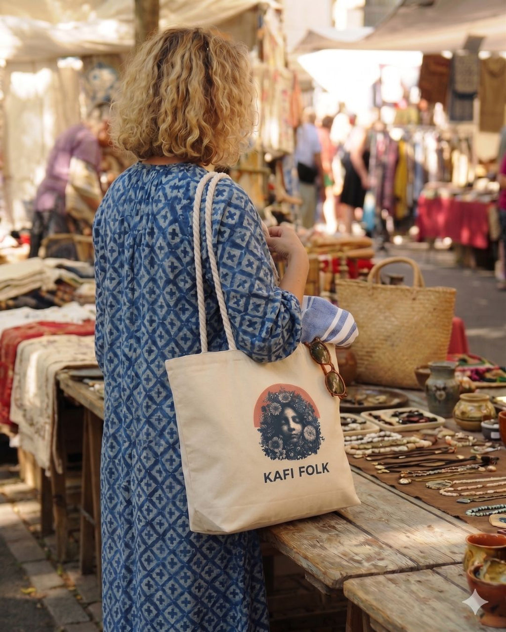 Woman shopping at an outdoor market with a 'Kafi Folk' tote bag.